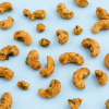 Losse dry roasted cashewnoten sour cream & onion op een lichtblauwe achtergrond