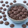 Cacaovrije melkdr​uppels ChoVia in decoratief schaaltje met druppels op de achtergrond