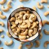 Schaaltje gevuld met geroosterde gezouten cashewnoten, omringd door losse cashewnoten
