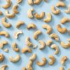 Los verspreide geroosterde gezouten cashewnoten op een lichtblauwe achtergrond