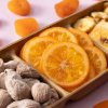 Gekonfijte sinaasappelschijfjes in een houten schaal met noten en gedroogd fruit