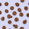 Cookie crumble rotsjes melk verspreid over een lichtpaarse achtergrond