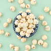 Schaaltje met witte chocolade popcorn en losse stukjes popcorn eromheen