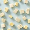 Losse blokjes soft nougat limoncello verspreid over een lichtblauwe achtergrond
