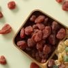 Houten bakje met gedroogde aardbeien en gekonfijt fruit ernaast