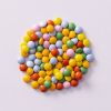Chocolade mini smarties op lichtpaarse achtergrond