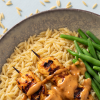 Close-up van een orzogerecht met gegrilde kip, sperziebonen en saus