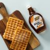 Biologische ahornsiroop met wafels op een houten serveerplank
