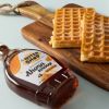 Close-up van een fles biologische ahornsiroop met wafels