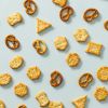 Crackers en pretzels uit de funky mix verspreid over een lichtblauwe achtergrond