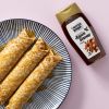 Biologische agavesiroop naast een bord met opgerolde pannenkoeken