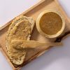 Brood met gemengde notenpasta en een open pot op een houten plank