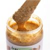 Lepel met smeuïge gemengde notenpasta boven een open pot