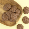 Melkchocolade chips rotsjes op houten schaal en gele achtergrond
