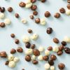 Biologische chocolade rozijnen verspreid over een lichtblauwe achtergrond