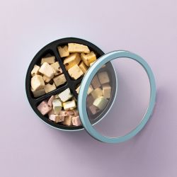 Bewaarblik met vier vakken gevuld met verschillende soorten nougat en los deksel