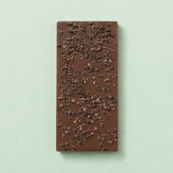 Melkchocoladereep met cacaonibs op een lichtgroene achtergrond