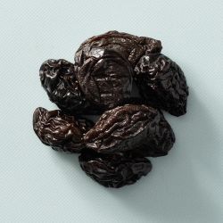 Gedroogde pruimen met pit op een lichtblauwe achtergrond