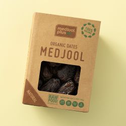 Biologische Medjoul dadels in een kartonnen verpakking op een lichtgele achtergrond