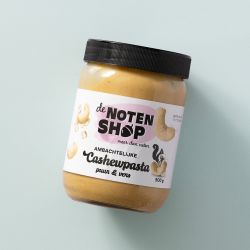 Pot ambachtelijke cashewpasta op een lichtblauwe achtergrond
