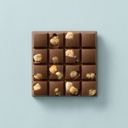 Melkchocolade choc block met stukjes hazelnoot op een lichtblauwe achtergrond