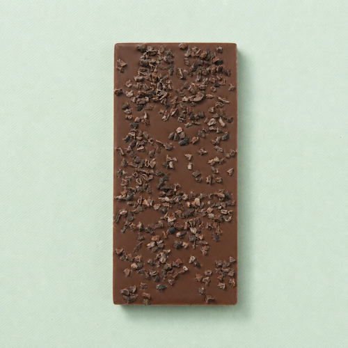 Melkchocoladereep met cacaonibs op een lichtgroene achtergrond Melkchocoladereep met cacaonibs op een lichtgroene achtergrond