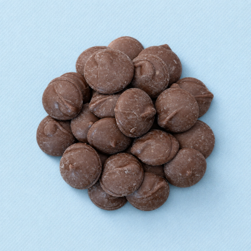 Cacaovrije melkdruppels ChoVia op lichtblauwe achtergrond Cacaovrije melkdruppels ChoVia op lichtblauwe achtergrond