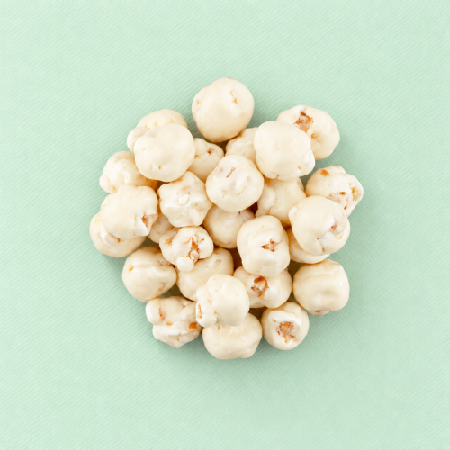 Popcorn omhuld met witte chocolade op een lichtgroene achtergrond Popcorn omhuld met witte chocolade op een lichtgroene achtergrond