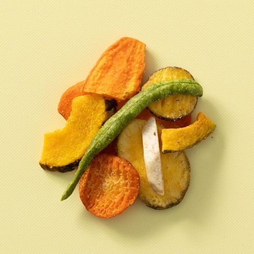 Groentechips van verschillende groenten op een lichtgele achtergrond