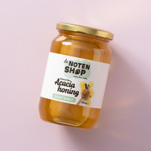 Pot acaciahoning op een lichtroze achtergrond