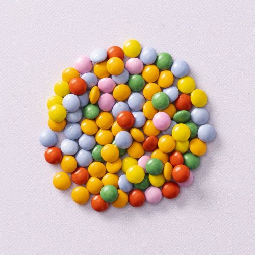 Chocolade mini smarties op lichtpaarse achtergrond Chocolade mini smarties op lichtpaarse achtergrond