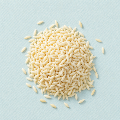 Hoopje biologische orzo op een lichtblauwe achtergrond Hoopje biologische orzo op een lichtblauwe achtergrond