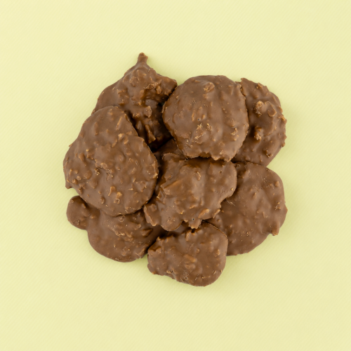 Melkchocolade rotsjes met krokante chips op gele achtergrond Melkchocolade rotsjes met krokante chips op gele achtergrond