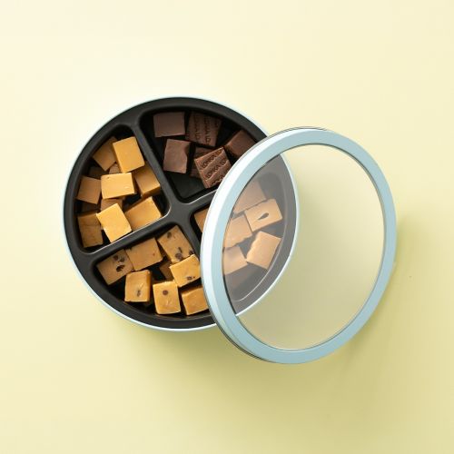 Bewaarblik met vier vakken gevuld met verschillende soorten fudge en los deksel Bewaarblik met vier vakken gevuld met verschillende soorten fudge en los deksel